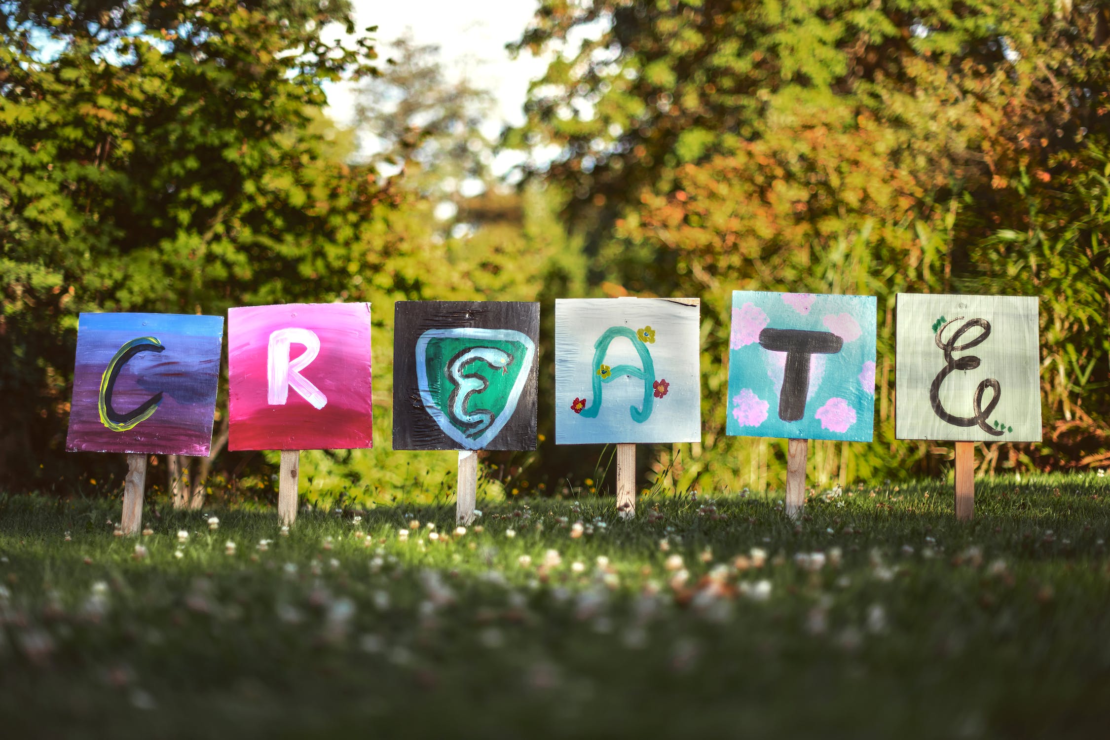 Colorful boards that spell "Create" in a park setting.