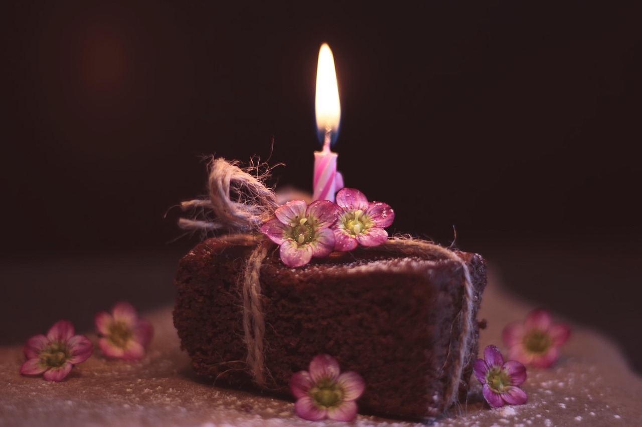 Image of brownie cake with pink flowers and candle lit