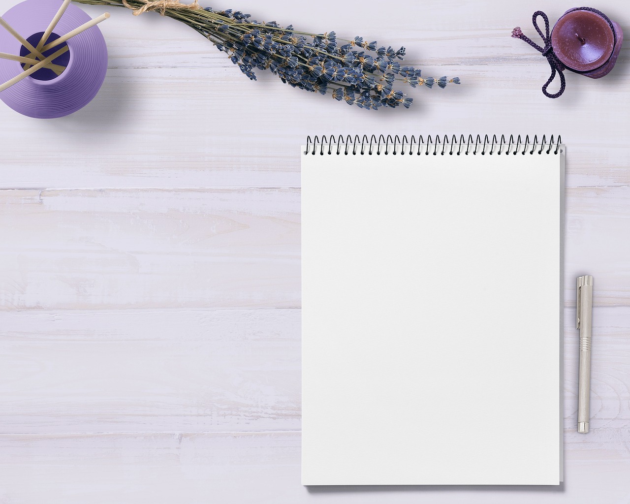 Image of writing pad with pen, candle, and flowers.