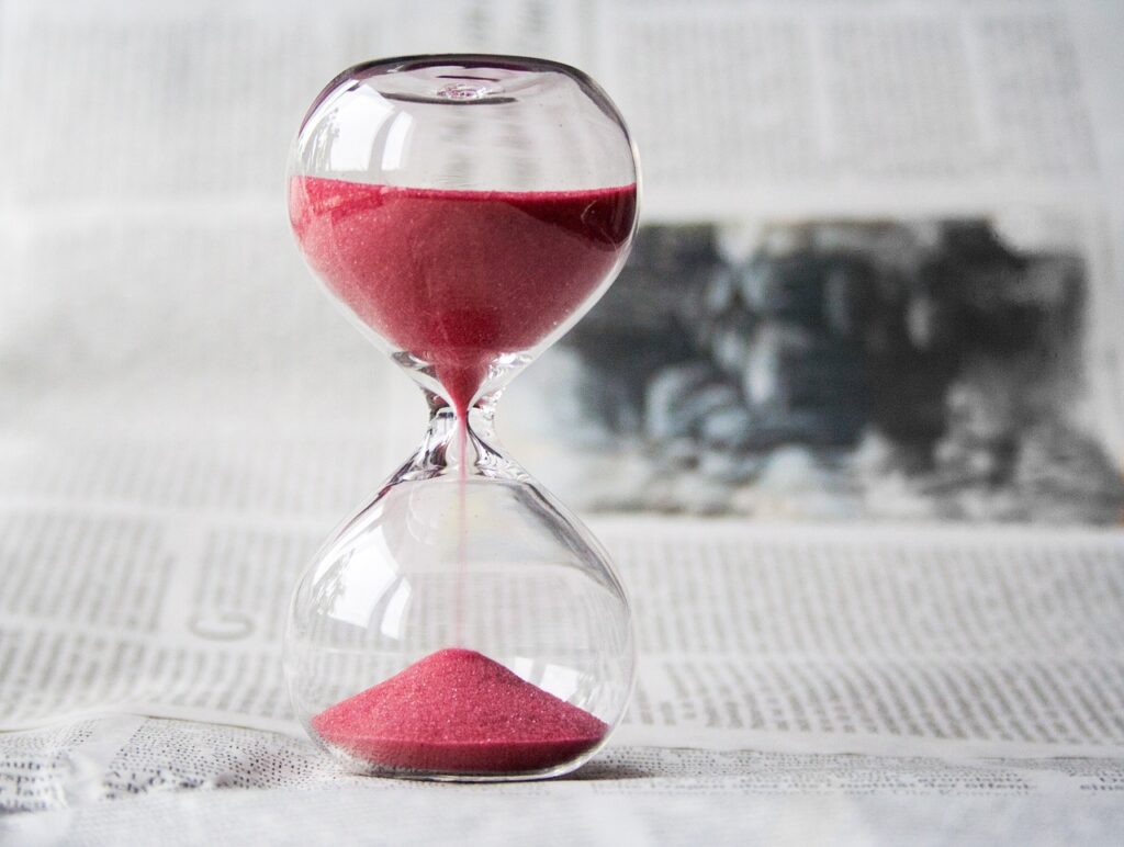 hourglass image with red sand, sitting on a newspaper