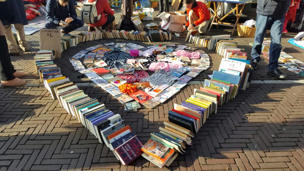 heart shape of various books, people looking through books, other items at an estate / garage sale       sale