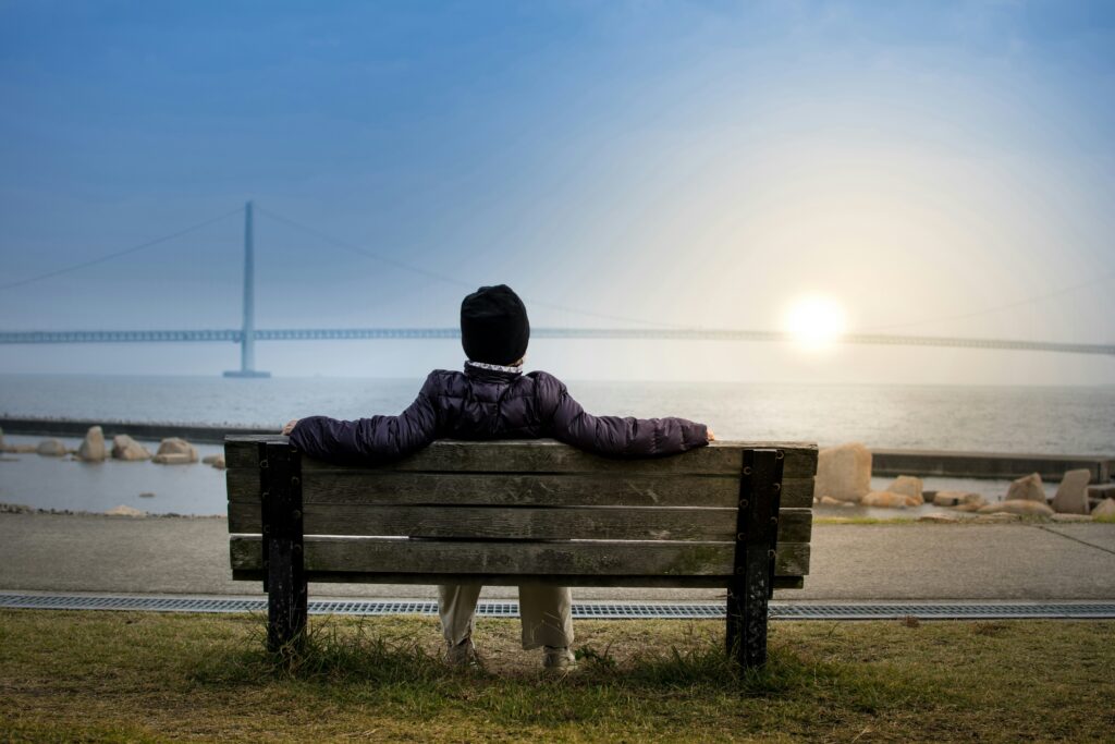 restful image looking at ocean, blue sky, light from the sun, wooden bench