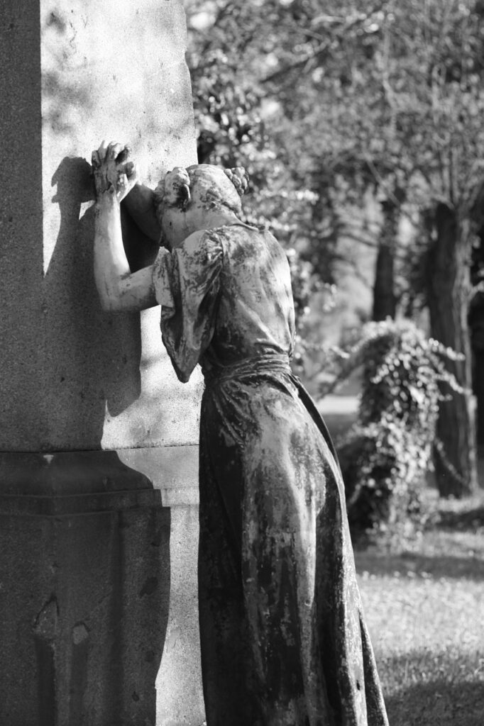 gravestone, sculpture, woman grieving, grey and black colors 