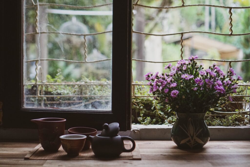 open window with tea set up and purple flowers