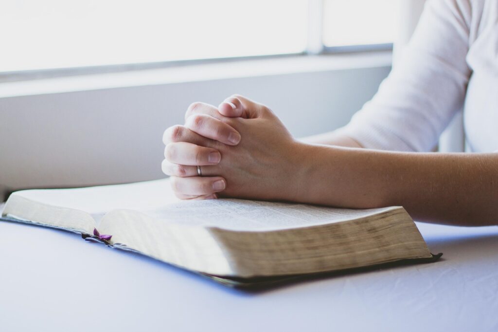 hand on Bible praying hands on Bible