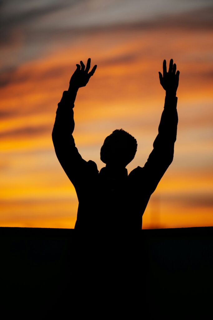 hands reaching to heaven a man reaching toward heaven, sunrise in the distance
